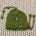 Vista completa gorro infantil crochet verde musgo Little Olive Elf con doble cordón de mini pompones — LIA.G