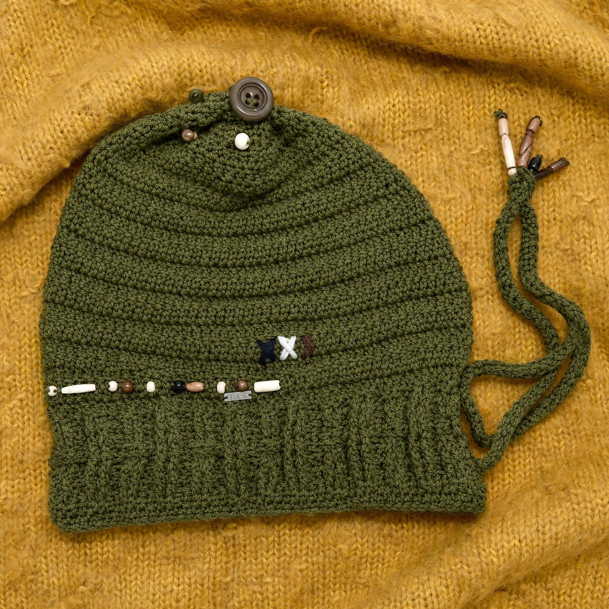 Vista completa gorro crochet verde oliva Olive Trail con cordón lateral y botón en coronilla — LIA.G
