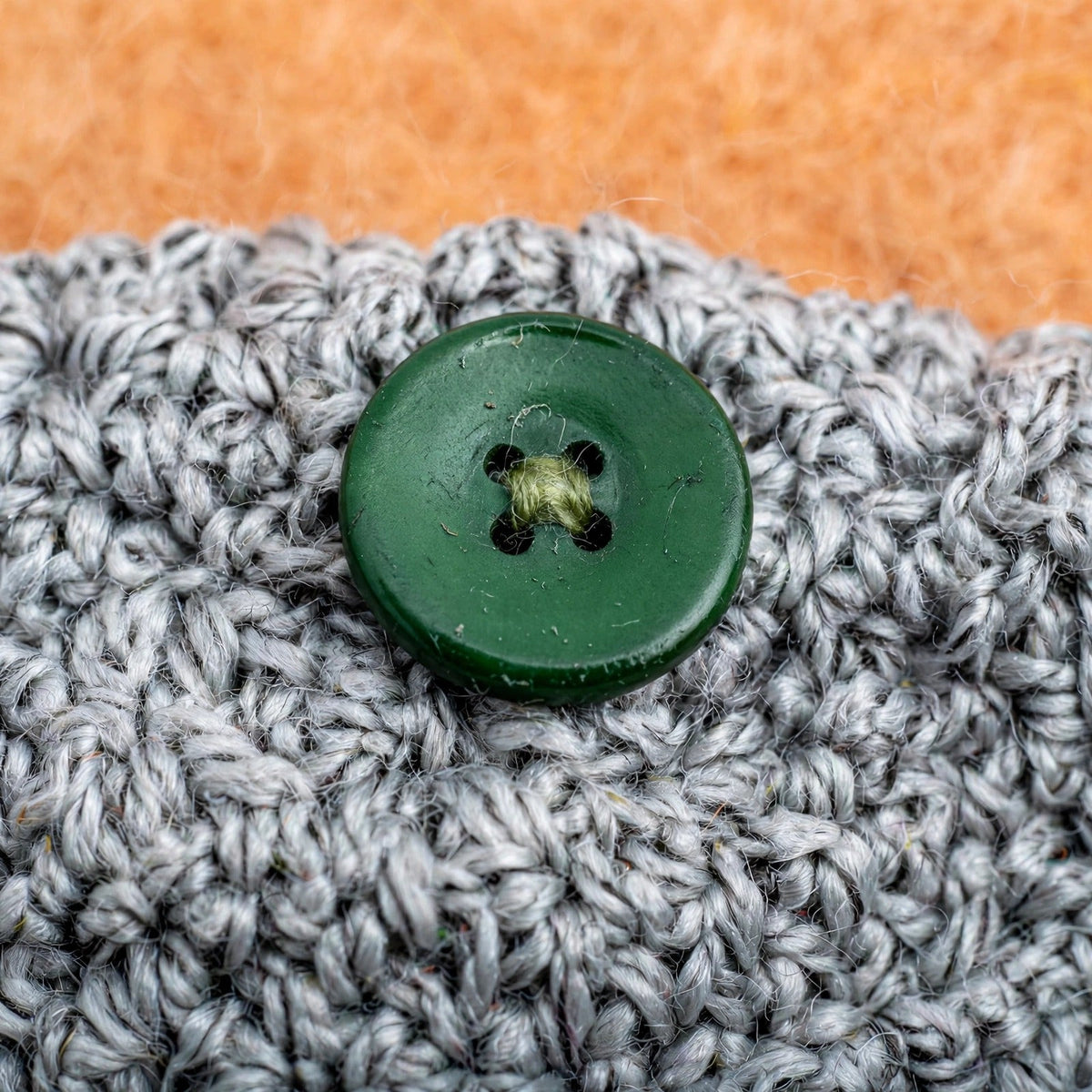 Detalle macro botón verde de 4 agujeros cosido sobre punto musgo gris jaspeado — Moss Buckle LIA.G