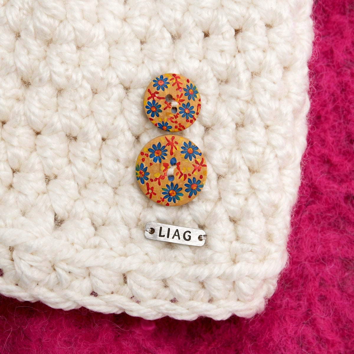 Detalle botones de madera pintados a mano motivo floral y etiqueta LIAG gorro Ivory Bloom