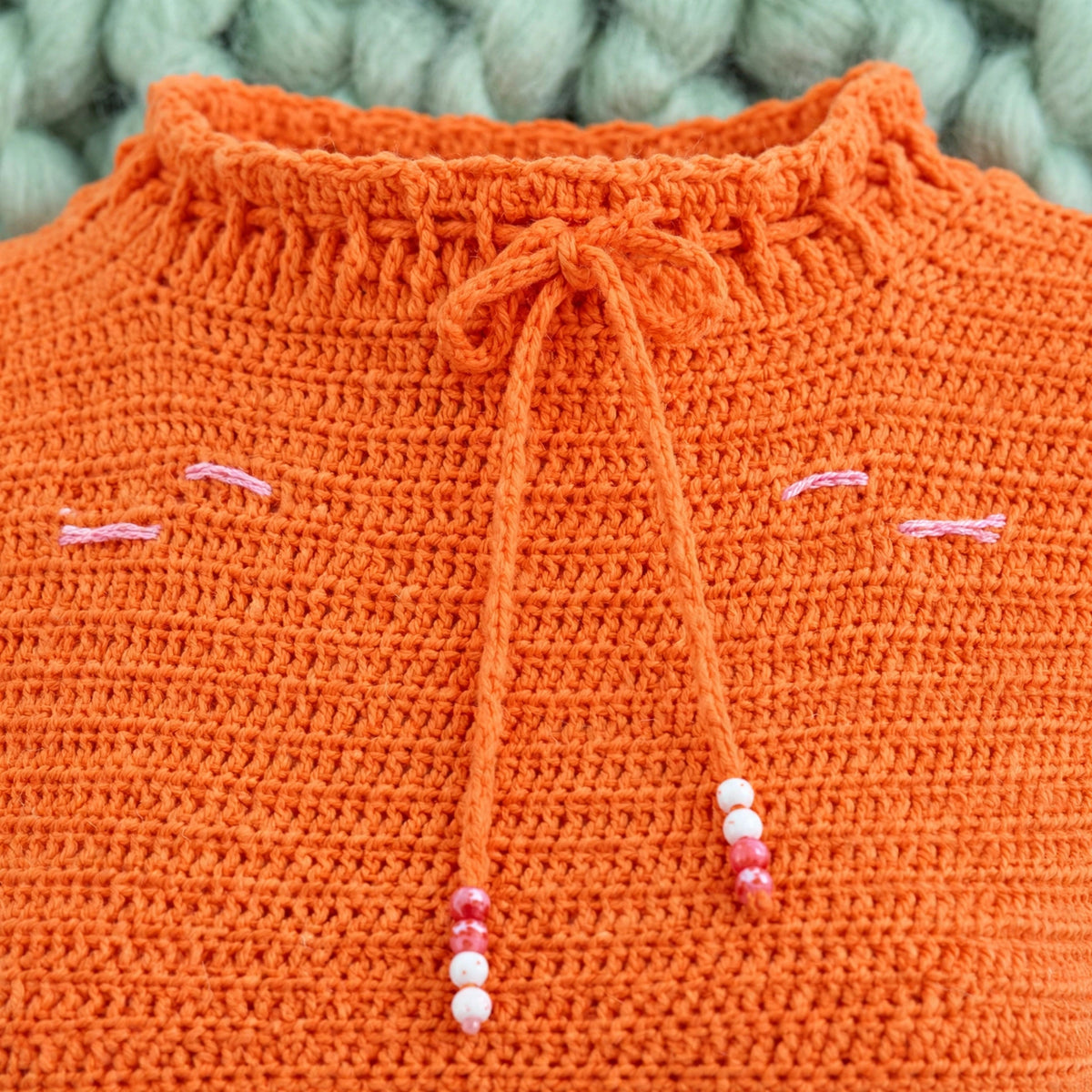 Detalle cuello alto lettuce edge con cordón y cuentas blusa crochet naranja