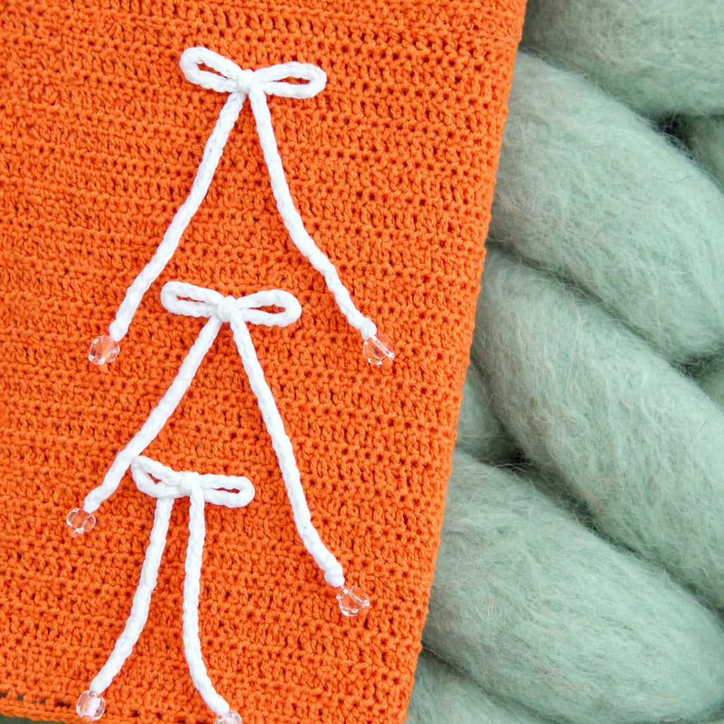 Detalle lazos blancos aplicados a mano con cuentas blusa crochet naranja