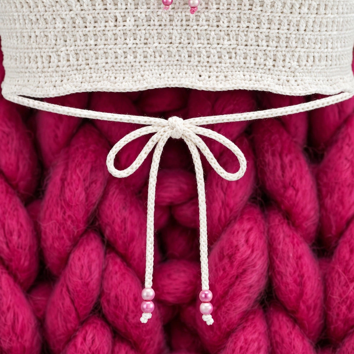 Detalle cordón cinch del bajo con lazo blanco y cuentas de perla rosa — Top Crochet Crudo LIA.G
