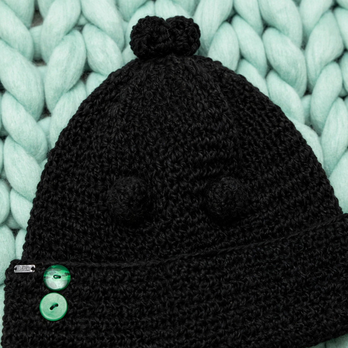 Detalle 2 mini pompones tejidos en el cuerpo del gorro y 1 en coronilla — Noir Wrap LIA.G