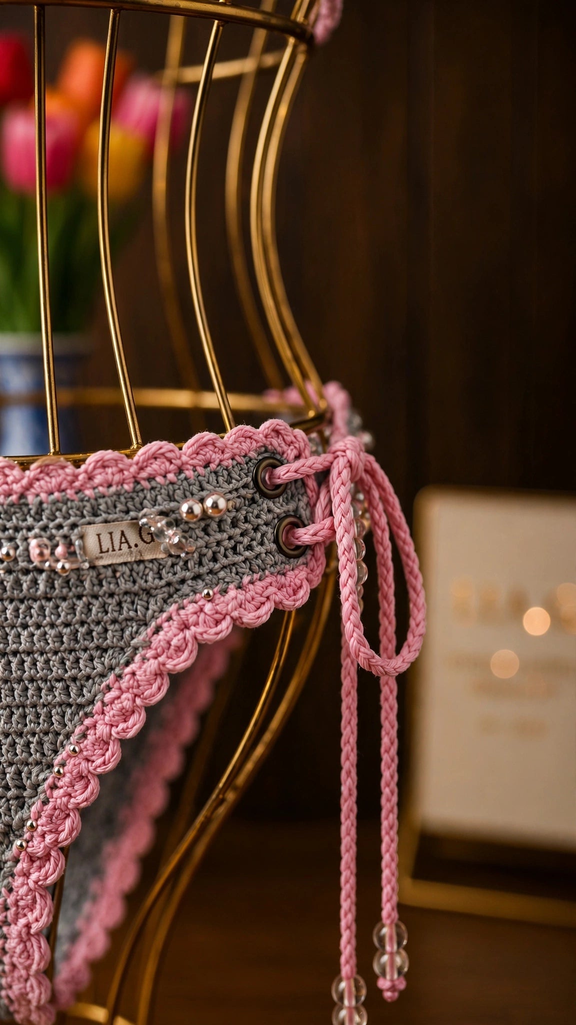 Detalle braguita bikini crochet gris con lazos rosa y etiqueta LIA.G