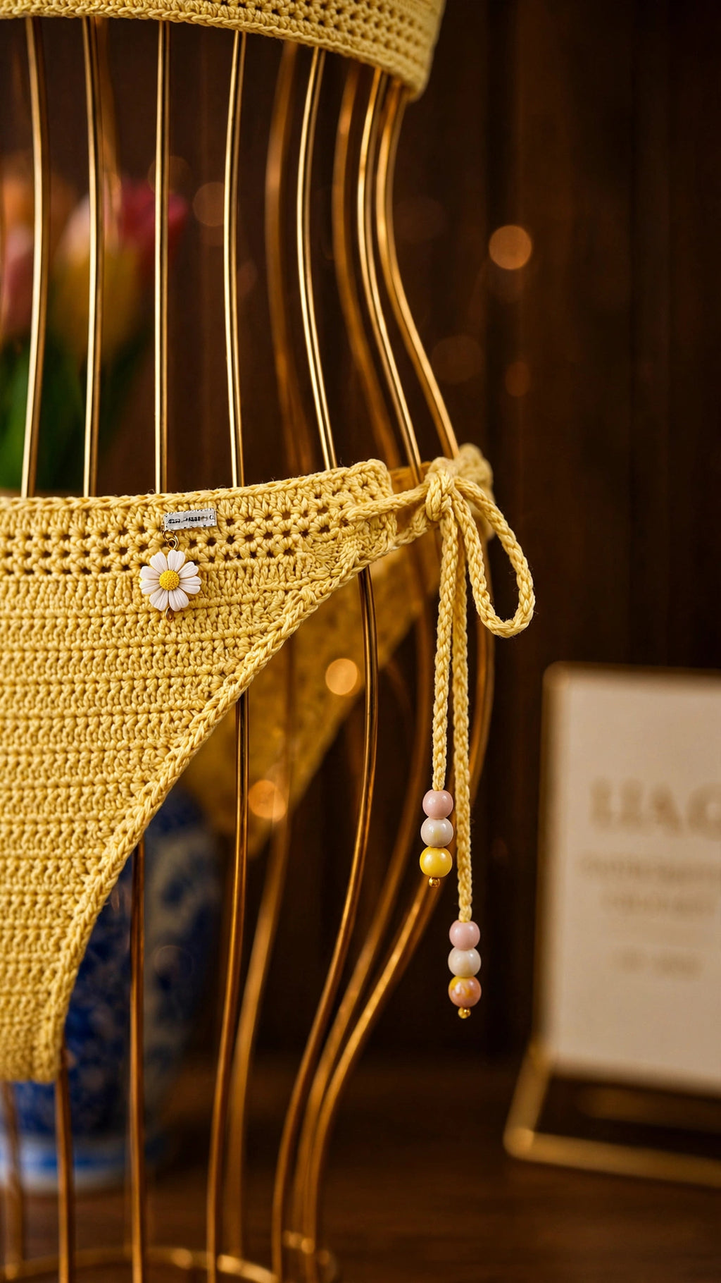 Detalle braguita bikini crochet amarillo con margarita blanca y cuentas pastel colgantes