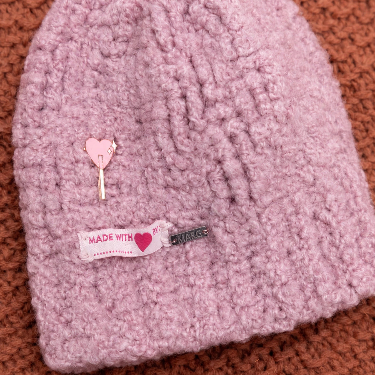 Detalle trenza en relieve y charm corazón gorro crochet Mauve Cable malva