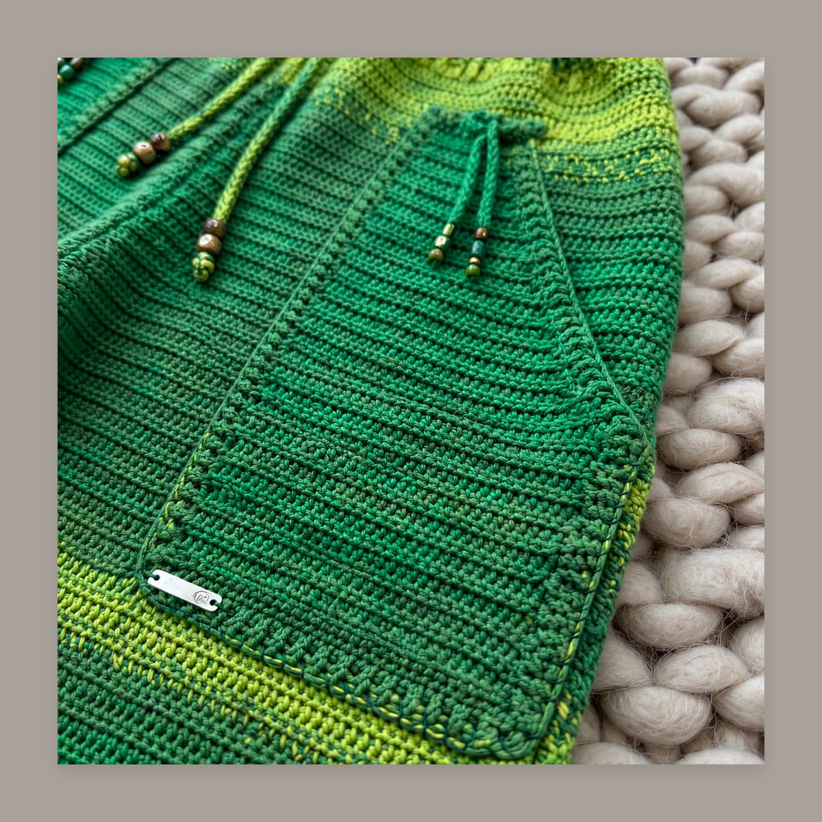 Detalle bolsillo con etiqueta textil LIA.G y cordón con cuentas — Pantalón Crochet Verde