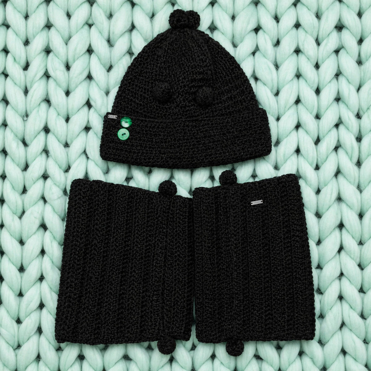 Conjunto completo Noir Wrap — gorro con pompones y bufanda extra larga crochet negro sobre fondo menta — LIA.G
